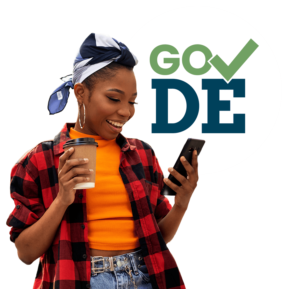 A smiling woman against a yellow backdrop looking down at a smart phone in her hand, the Go DE logo in the background.